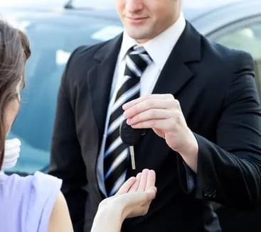 Remise des clés d’une voiture entre un homme en costume et une cliente