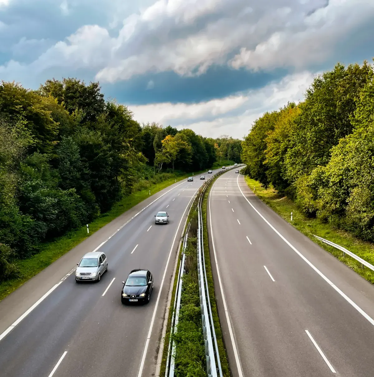 Vue aérienne d'une route à quatre voies bordée d'arbres avec plusieurs voitures