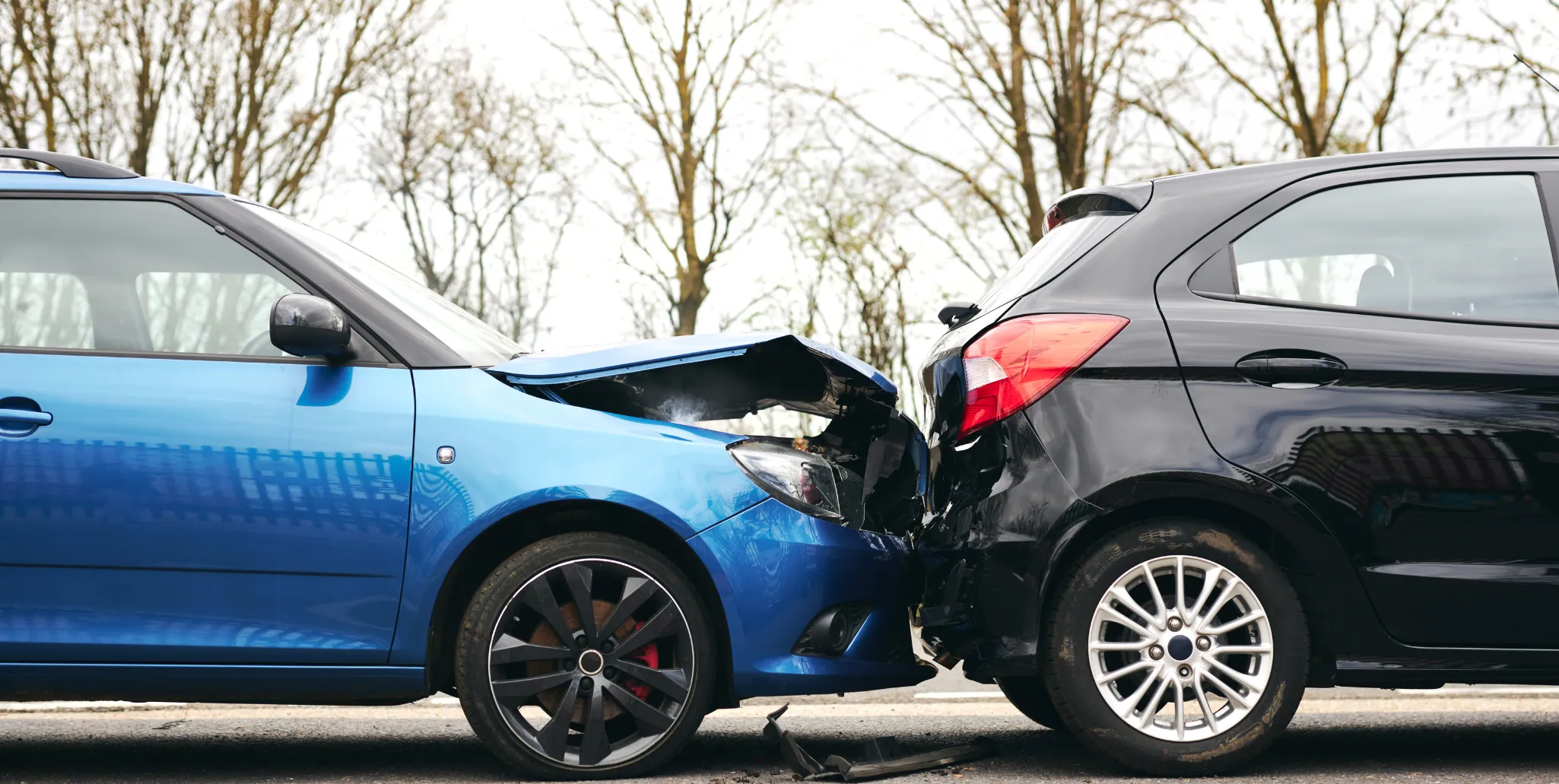 Collision entre deux voitures, l'une bleue et l'autre noire, à l'arrêt sur la route