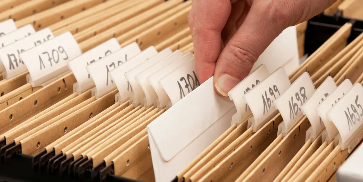 Personne consultant une pile de dossiers et de documents d'archives