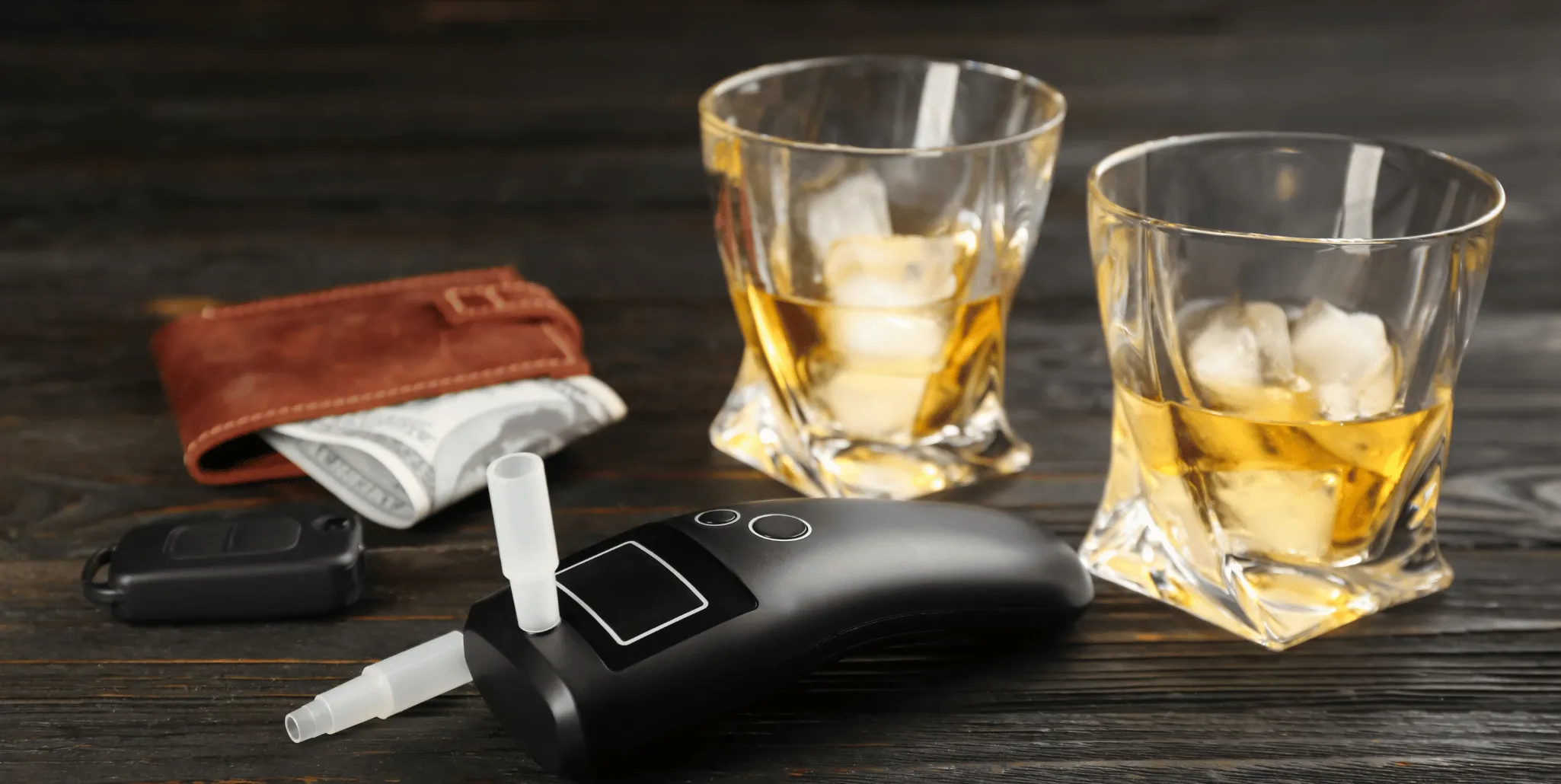 Clés de voiture, portefeuille et éthylotest posés près de deux verres d'alcool