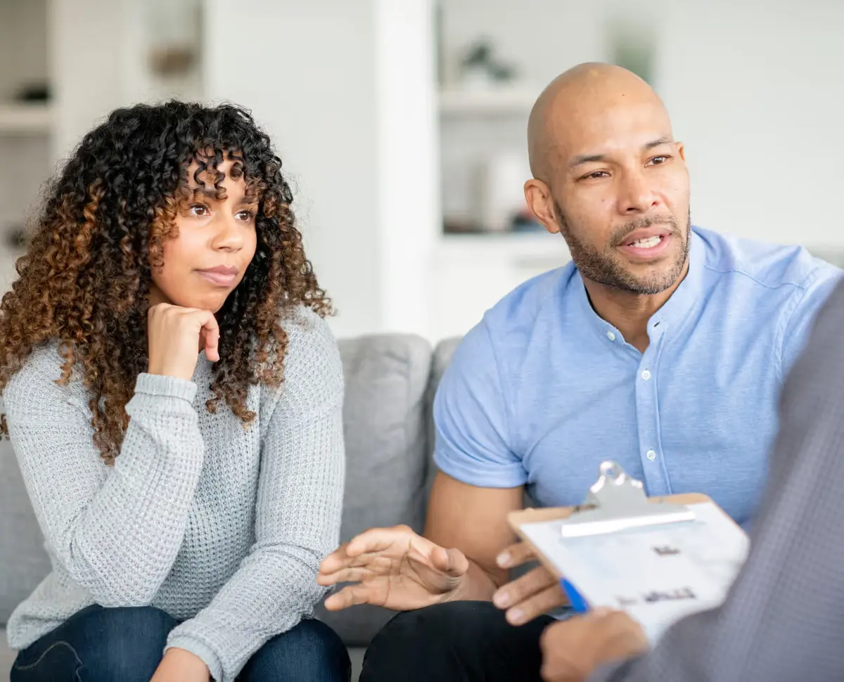 Couple en consultation avec un conseiller tenant un dossier