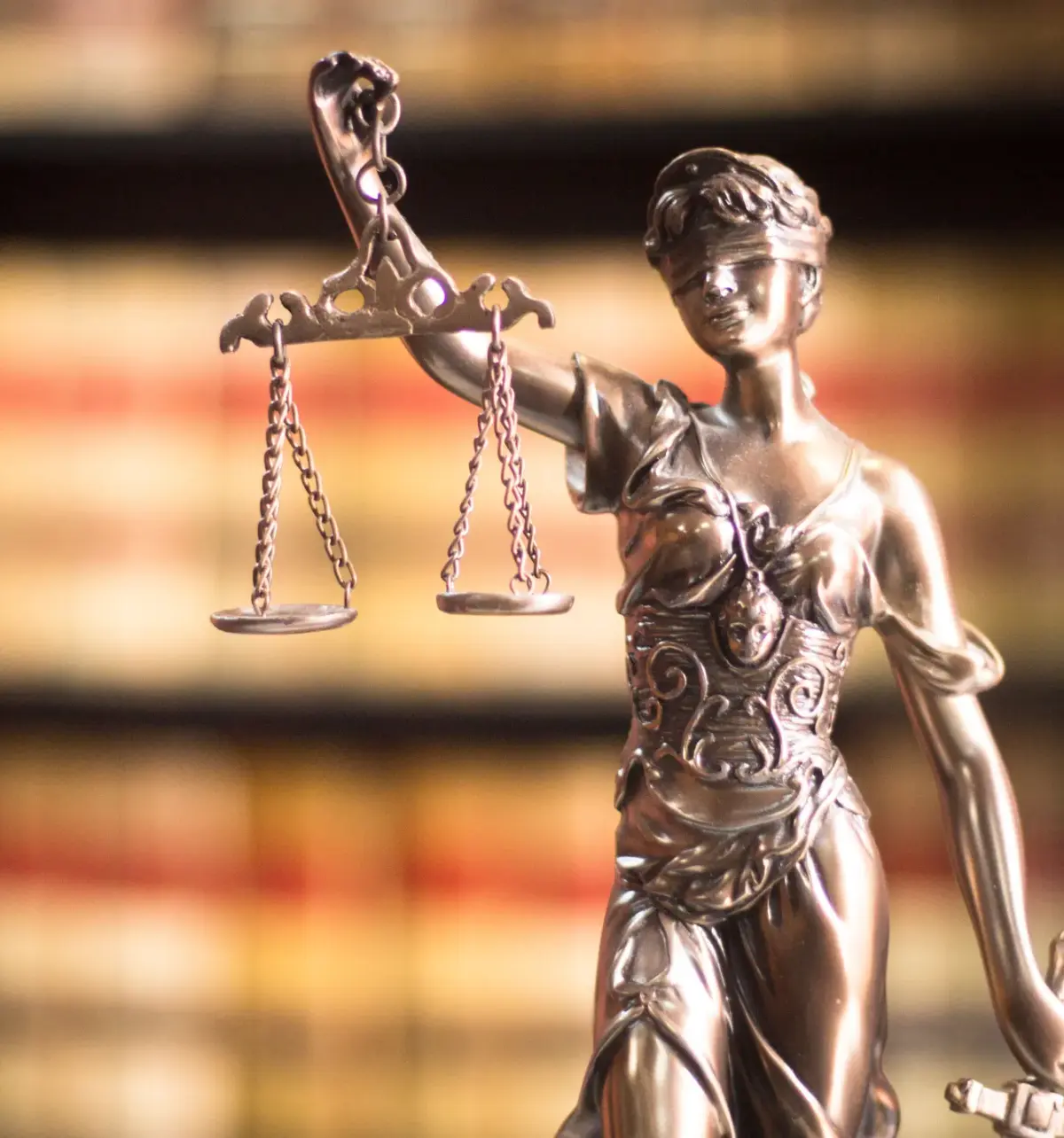 Statuette dorée de la Justice tenant une balance, devant une bibliothèque