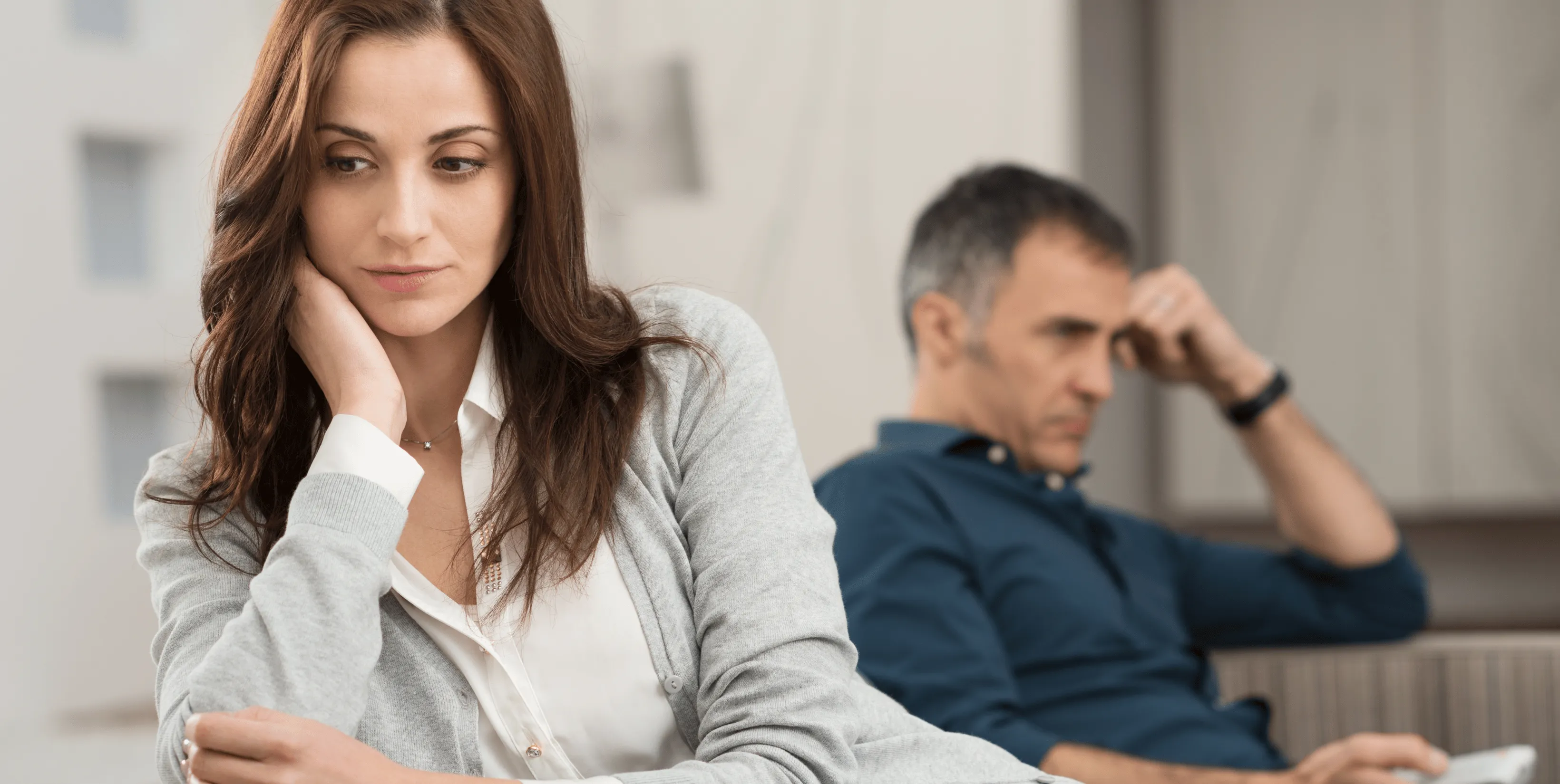 Femme visiblement affectée assise au premier plan, homme en arrière-plan
