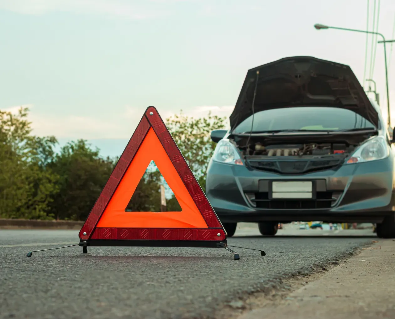 Triangle de signalisation posé sur la route devant une voiture accidentée