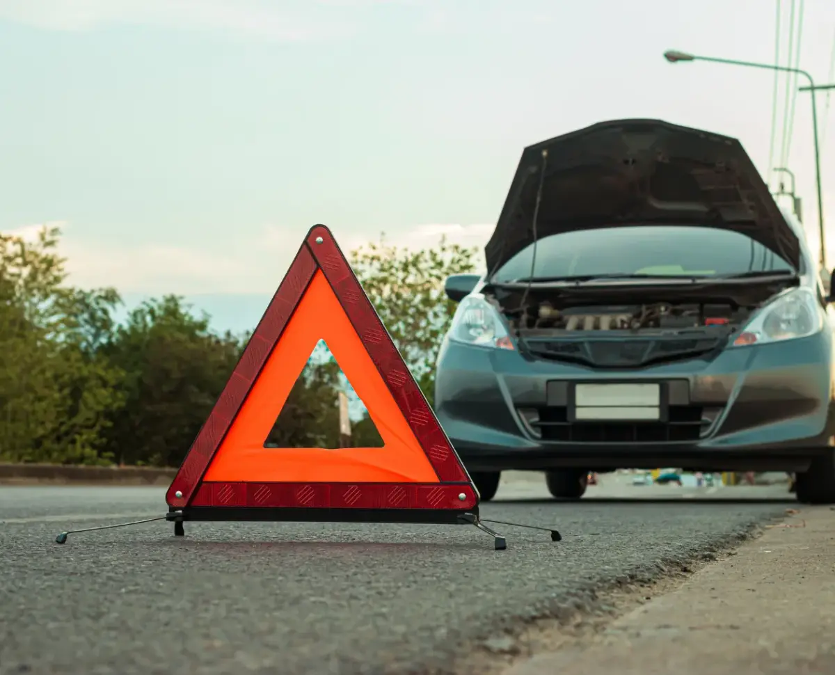 Triangle de signalisation posé devant une voiture en panne sur la route